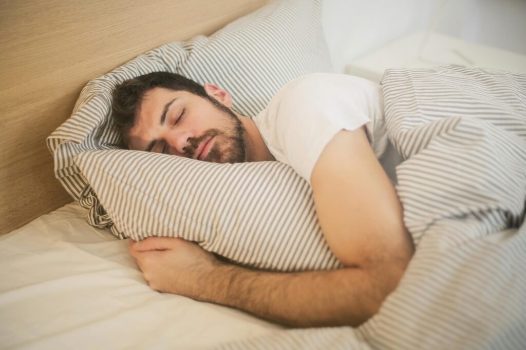 Morning Fatigue in Men: It’s Not Always Low T Man sleeping peacefully on striped bedding, embracing relaxation and comfort.