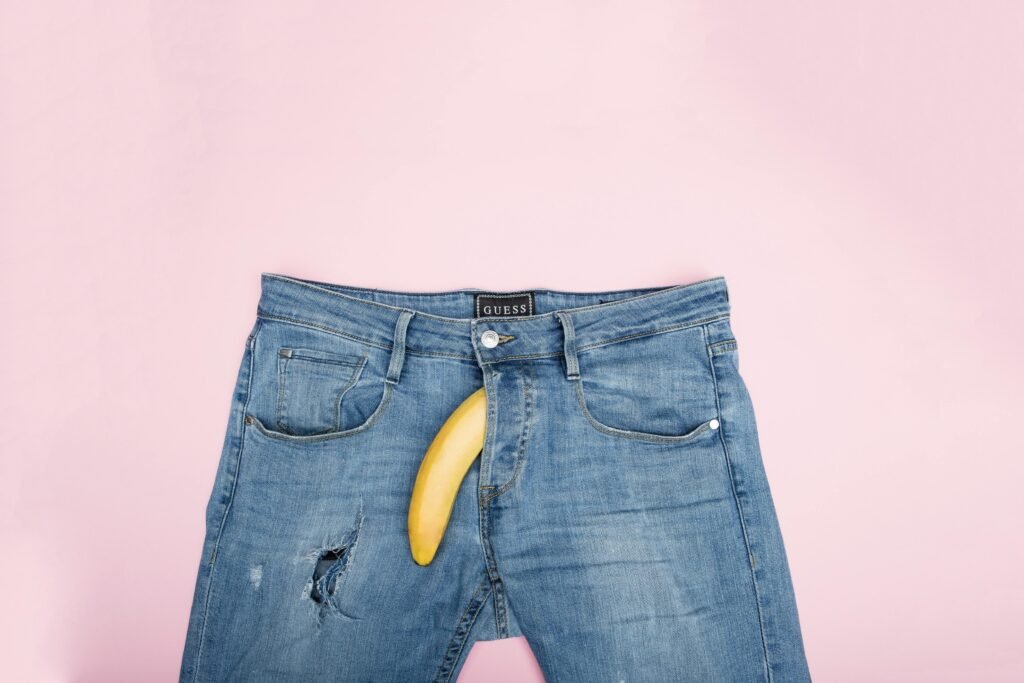 Why Do So Many Young Men Think They Have Low Testosterone? A creative still life featuring blue jeans and a banana against a pink backdrop.
