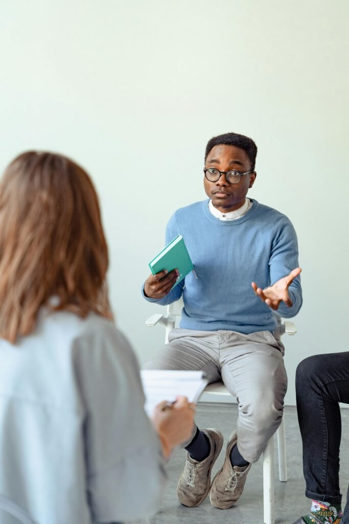 Why Do So Many Young Men Think They Have Low Testosterone? Male therapist engaging clients during a therapy session indoors, promoting mental health awareness.